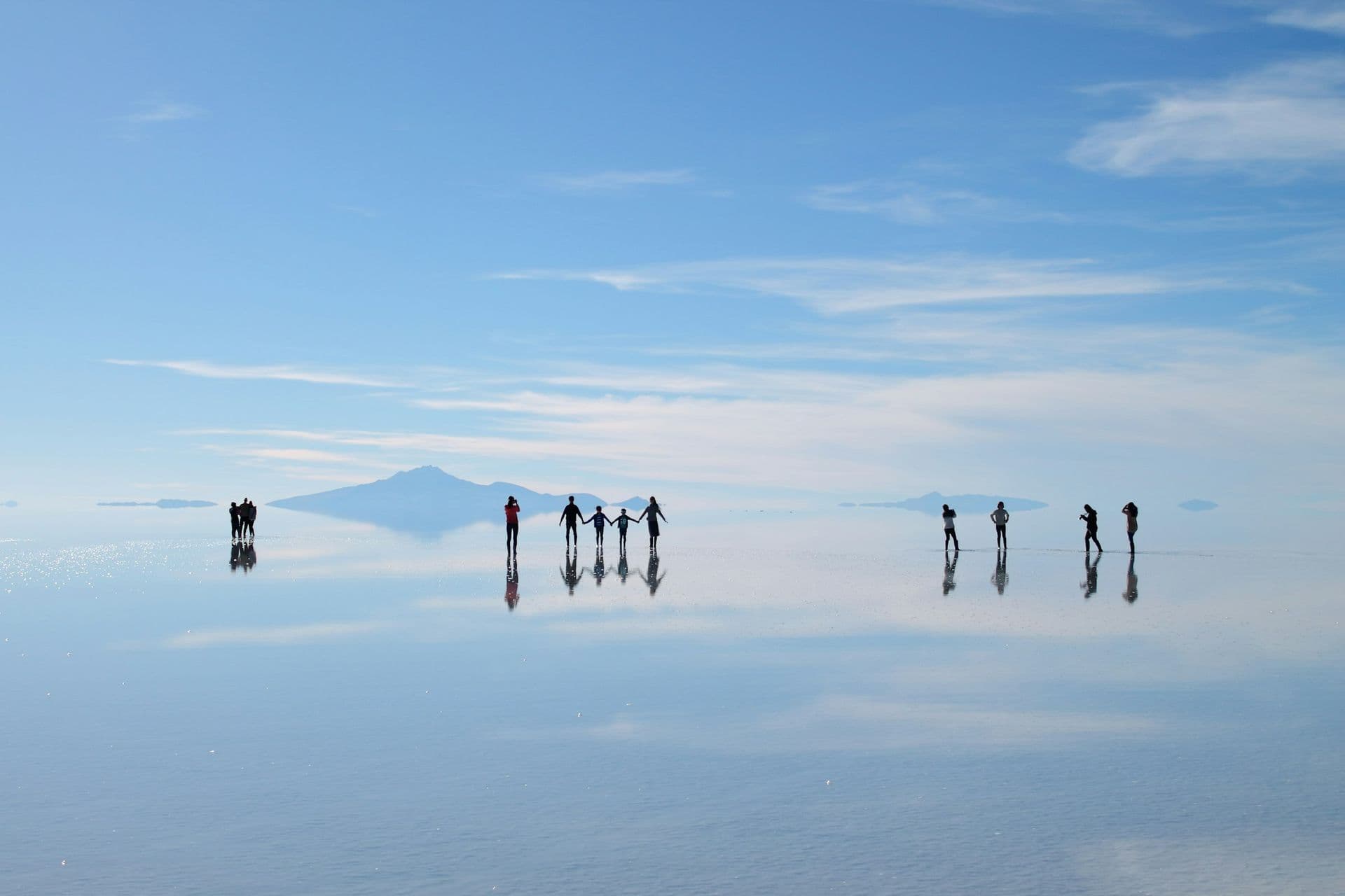 Travellers reflected in a thin layer of water on the Salar de Uyuni