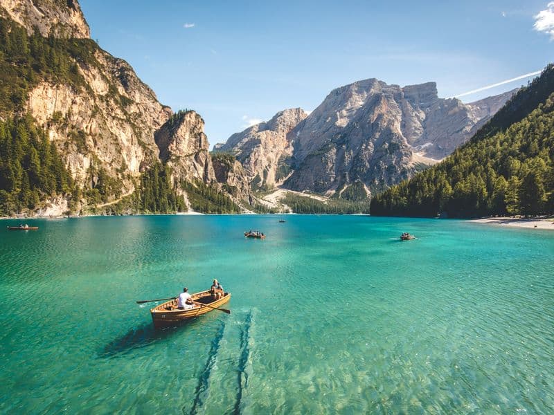 A rowing boat on the green water of a lake below the Dolomites