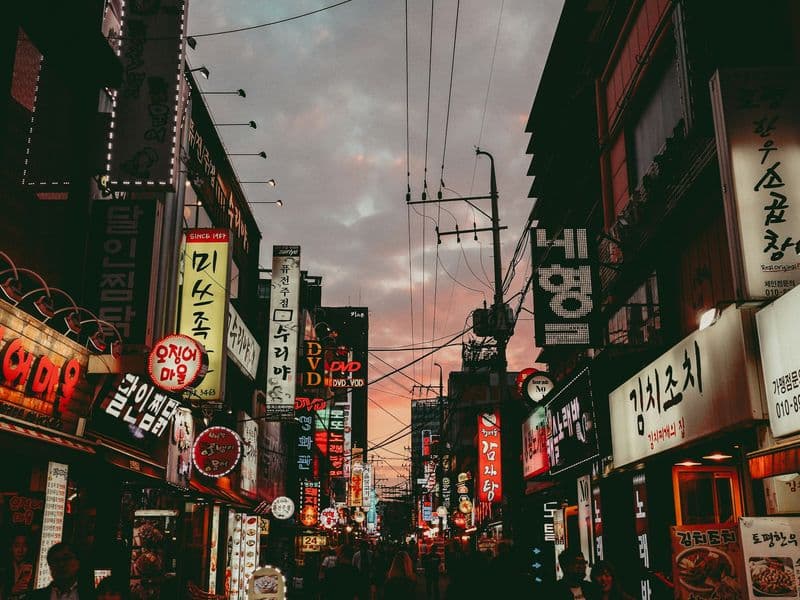 A busy Seoul street at dusk lined with Korean shop signs