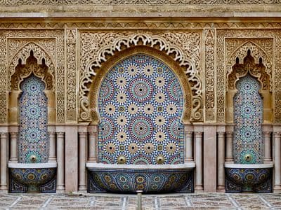 A tiled fountain with carved arches in Morocco