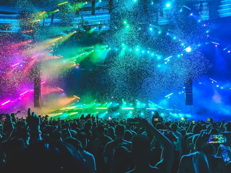 A festival crowd under colourful stage lights and confetti