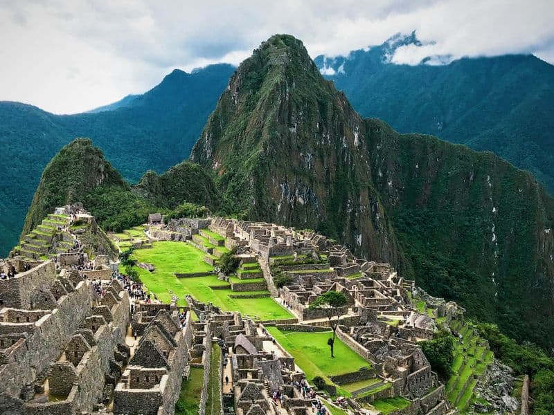 Machu Picchu ruins below a green mountain peak