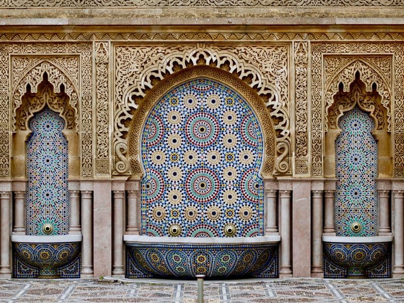 Moroccan zellige tiles and carved arches around a fountain