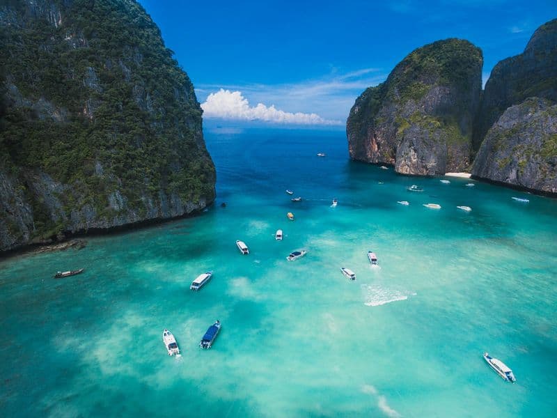 Boats in turquoise water between limestone cliffs at Maya Bay
