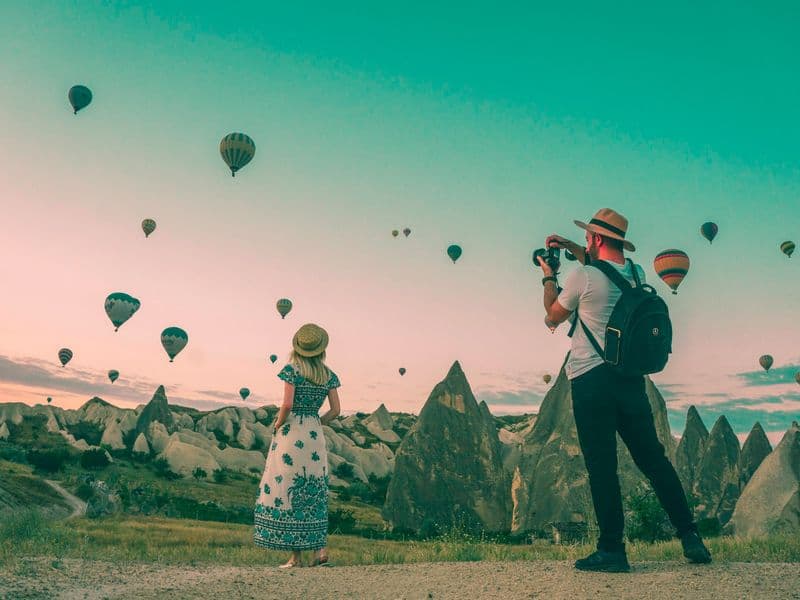 Travellers watching hot-air balloons rise over Cappadocia
